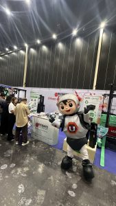 Mr.U mascot in front of booth United Motor Works at Logistics Automation Expo 2026